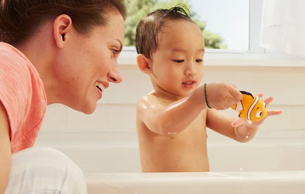 Toddler playing with a Finding Nemo bath toy